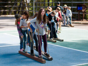 A group of children walk on tandem boards