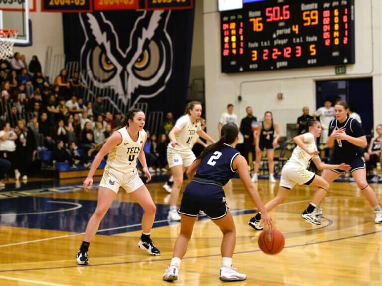 Women of the Oregon Tech basketball team face off against opponents on the court.