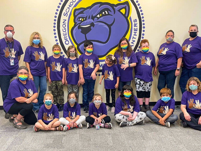 A group of students pose in front of a panther mascot.